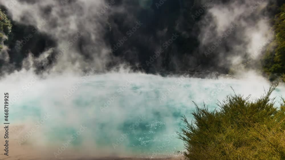 Tilt down shot of Steam rising up to sky from boiling Inferno Crater Lake during sunny day in New Zealand