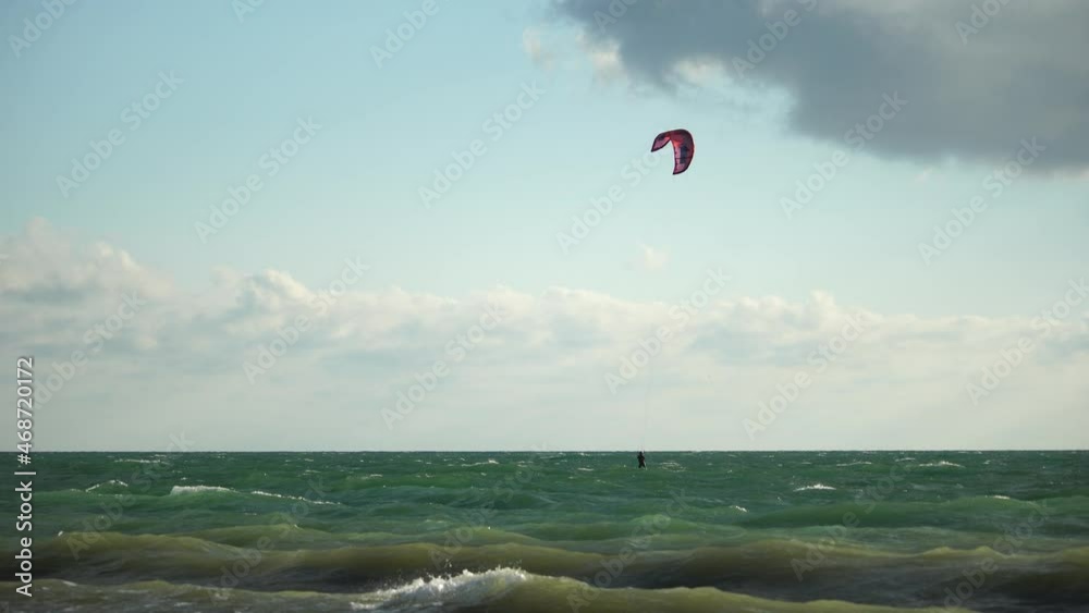 Kitesurfing on the waves of the emerald sea. The man is kiteboarding in the turquoise sea water. The man on the board quickly floats through the waves. Summer vacation. Kitesurfing on the waves of the emerald sea. The man is kiteboarding in the turquoise sea water. The man on the board quickly floats through the waves. Summer vacation.