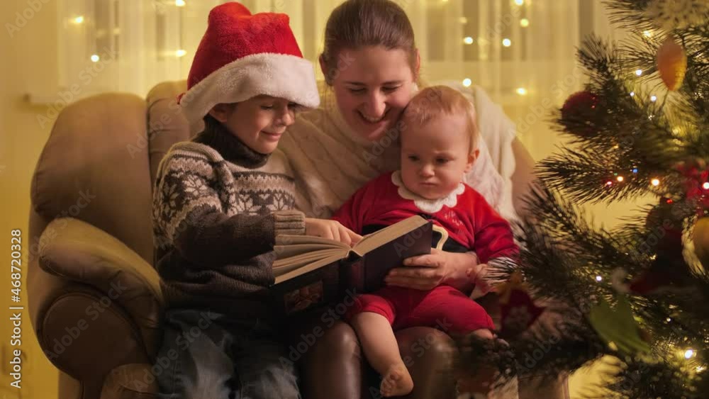 Baby boy with brother and mother reading fairy tale book on Christmas eve . Families and children celebrating winter holidays. Baby boy with brother and mother reading fairy tale book on Christmas eve . Families and children celebrating winter holidays.