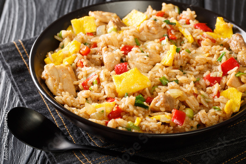 Peruvian fried rice with chicken, omelet, peppers and onions close-up in a bowl on a wooden table. horizontal