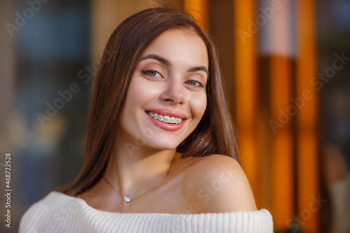 portrait of a beautiful happy smiling young woman with braces. girl bracket system  outdoor. Brace, bracket, dental care, malocclusion, orthodontic health concept. Blurred Details photo