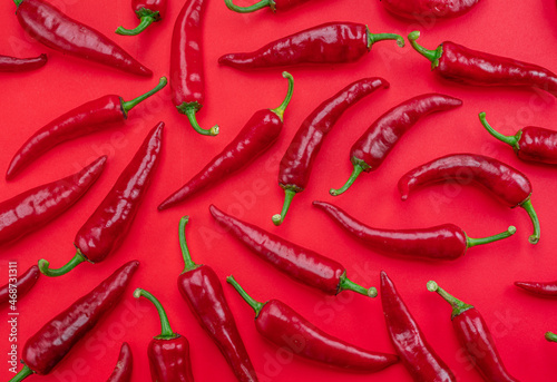 Seamless pattern done of red chilli peppers isolated on red background. photo