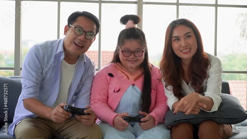 Family of three with Father mother and one Autistic Child is playing Video game together in home living room.