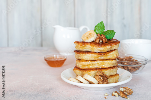 Breakfast with pancakes with honey and nuts on a light background.