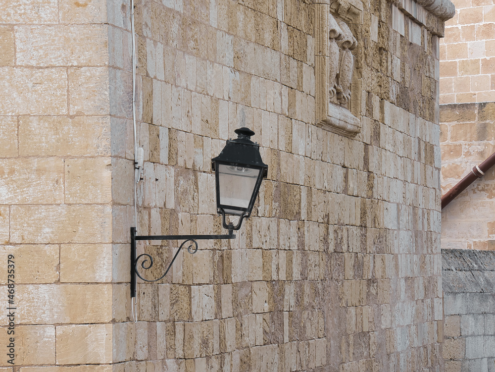 a damaged streetlamp on a stone house wall a damaged streetlamp on a stone house wall
