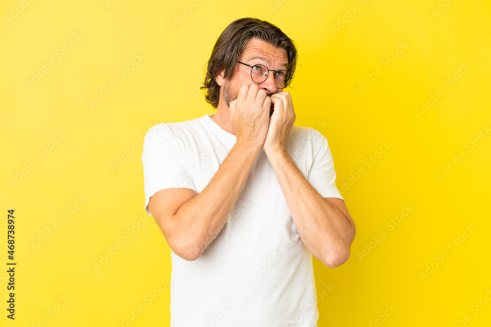 Senior dutch man isolated on yellow background nervous and scared putting hands to mouth Senior dutch man isolated on yellow background nervous and scared putting hands to mouth