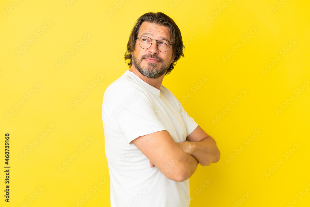 Senior dutch man isolated on yellow background with arms crossed and happy Senior dutch man isolated on yellow background with arms crossed and happy
