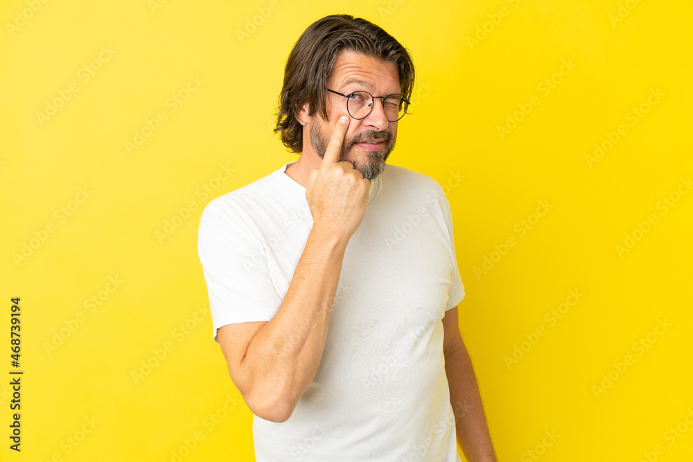 Senior dutch man isolated on yellow background showing something Senior dutch man isolated on yellow background showing something