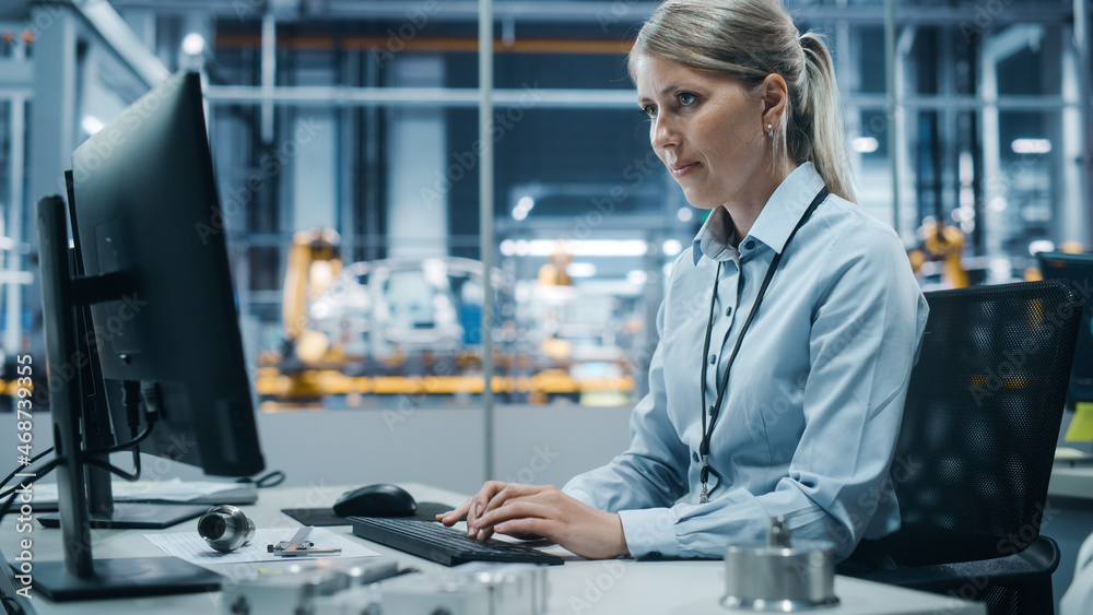 Car Factory Office: Portrait of Confident Female Chief Engineer Working on Desktop Computer. Professional Technician in Automated Robot Arm Assembly Line Manufacturing High-Tech Electric Vehicles Car Factory Office: Portrait of Confident Female Chief Engineer Working on Desktop Computer. Professional Technician in Automated Robot Arm Assembly Line Manufacturing High-Tech Electric Vehicles