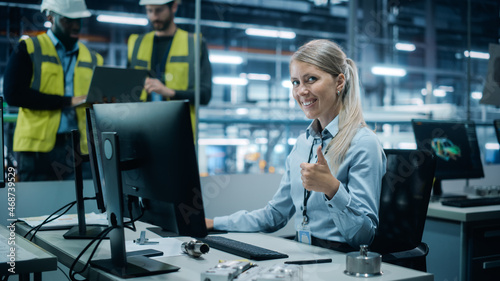 Car Factory Office: Portrait of Female Engineer Working on Desktop Computer, Smiling and Showing Thumbs up gesture. Team of Technicians in Automated Robot Arm Assembly Line Manufacturing Electronics