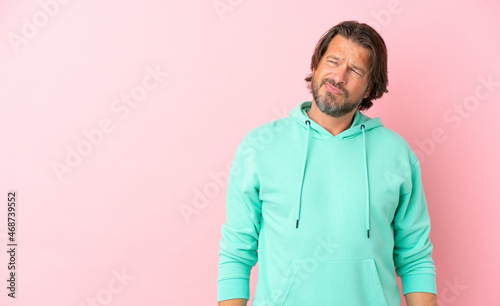 Senior dutch man isolated on pink background having doubts while looking side © luismolinero