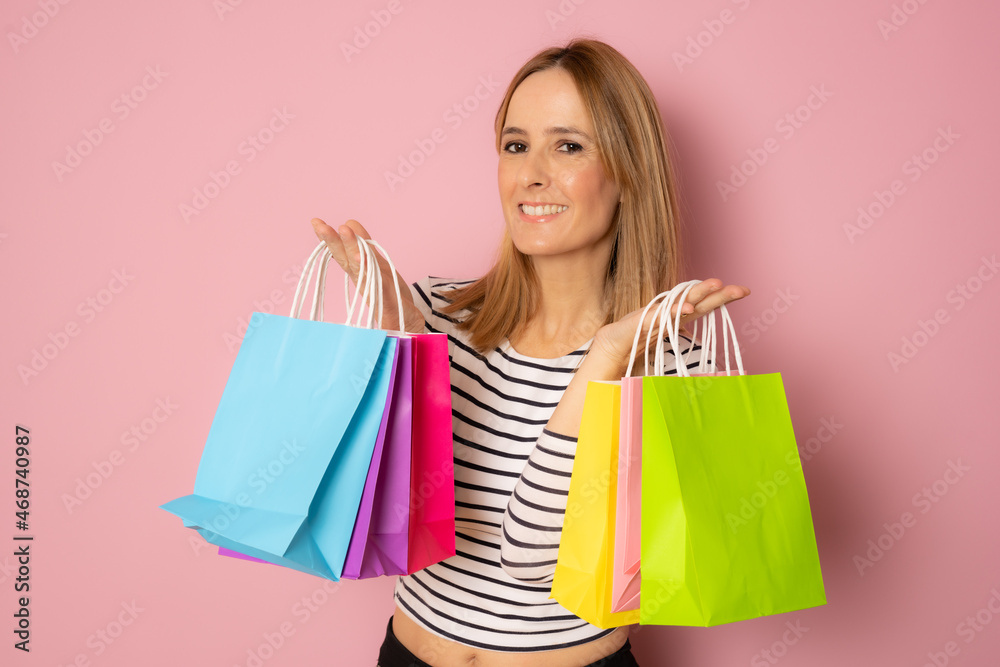 Portrait of a cheerful woman holding shopping bags and looking at camera isolated over pink background Portrait of a cheerful woman holding shopping bags and looking at camera isolated over pink background