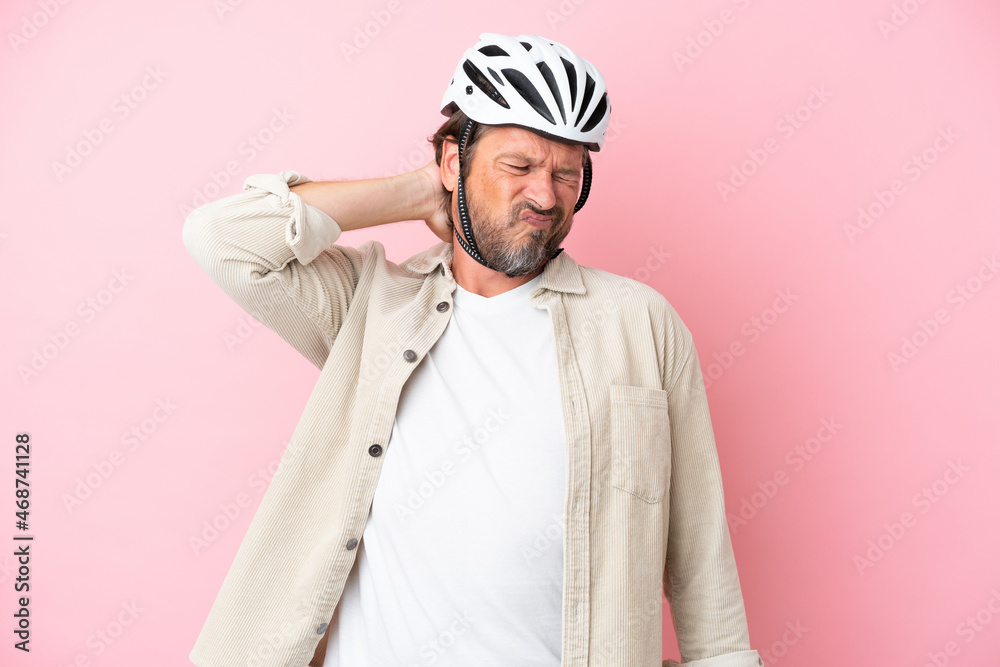 Senior dutch man with bike helmet isolated on pink background with neckache Senior dutch man with bike helmet isolated on pink background with neckache