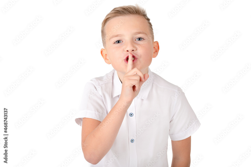 Top secret. Young schoolboy holding a finger on his lips, asking to keep silence about confidential information, saying shh, looking at the camera.Isolated white background.Copy space.Mockup. Top secret. Young schoolboy holding a finger on his lips, asking to keep silence about confidential information, saying shh, looking at the camera.Isolated white background.Copy space.Mockup.