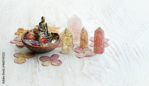 quartz minerals, little Buddha statue, dried flowers on white wooden table close up. Healing gemstones set for magic Crystal Ritual. Esoteric spiritual practice for harmony life balance, soul relax.