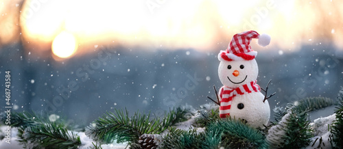 cute snowman toy on snowy fir tree, winter natural background. Christmas and New year holiday. winter festive season. banner. copy space