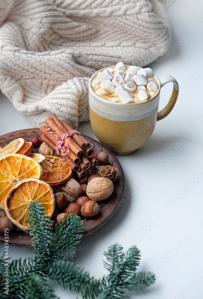 Coffee cup with marshmallows, sweater, fir branches, dried orange slices, cinnamon, nuts. atmosphere cozy winter season concept. New Year and Christmas holiday Coffee cup with marshmallows, sweater, fir branches, dried orange slices, cinnamon, nuts. atmosphere cozy winter season concept. New Year and Christmas holiday