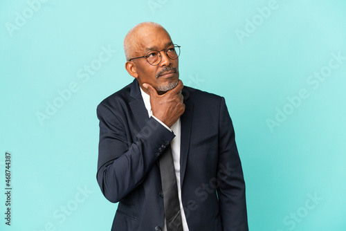 Business senior man isolated on blue background having doubts © luismolinero