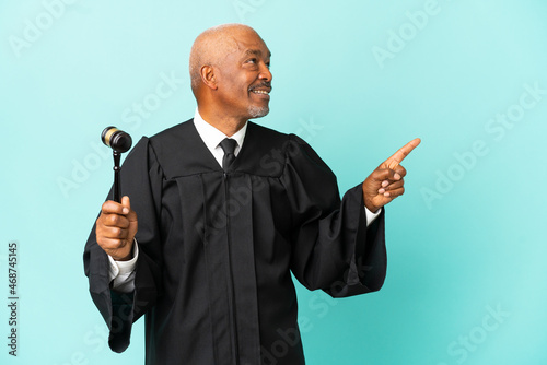 Fototapeta Judge senior man isolated on blue background pointing up a great idea