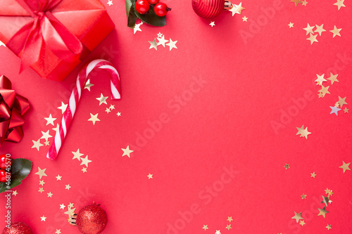 Christmas background, red gift box on red background and golden sparkling conffeti, candy cane.