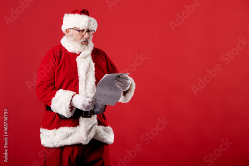 Santa Claus reading a letter on red background