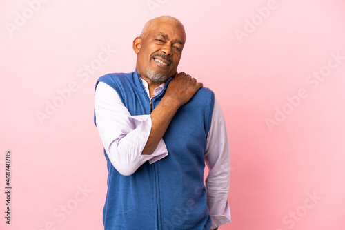 Cuban senior isolated on pink background suffering from pain in shoulder for having made an effort