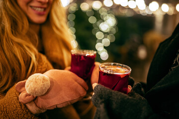 Close-up woman's hands in winter mittens with hot cup of hot mulled wine. Holidays, traditions, winter fair, Christmas concept