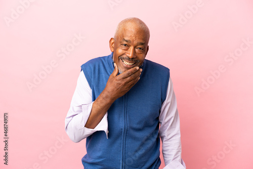 Cuban senior isolated on pink background happy and smiling covering mouth with hand