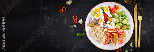 Breakfast oatmeal porridge with greek salad of tomatoes, cucumbers, olives, feta cheese and eggs. Healthy balanced food. Top view, flat lay