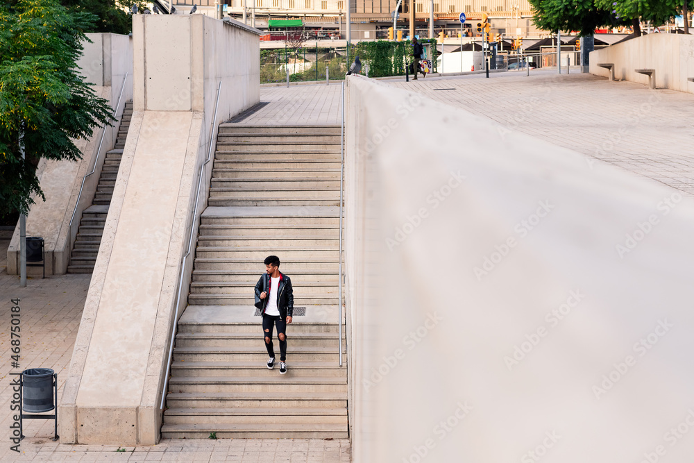 young latin man with backpack walking down stairs