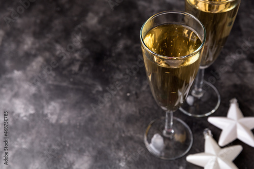 Two champagne glasses and Christmas ornaments on a black background. New year party concept