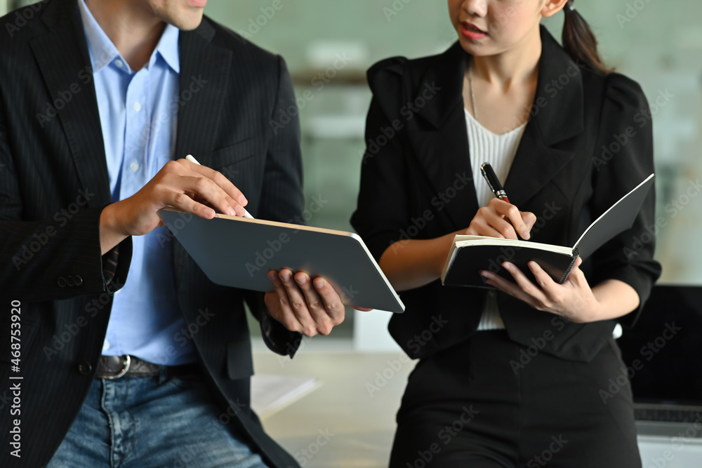 Closeup image of young business people working together at the working desk over a modern office as a background. Closeup image of young business people working together at the working desk over a modern office as a background.