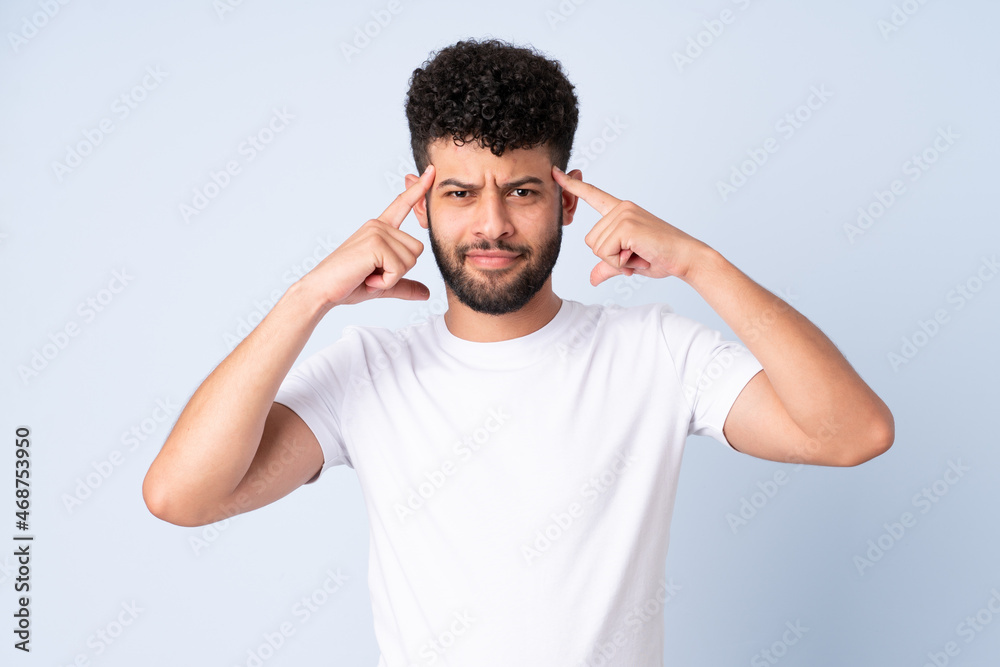 Young Moroccan man isolated on blue background having doubts and thinking Young Moroccan man isolated on blue background having doubts and thinking