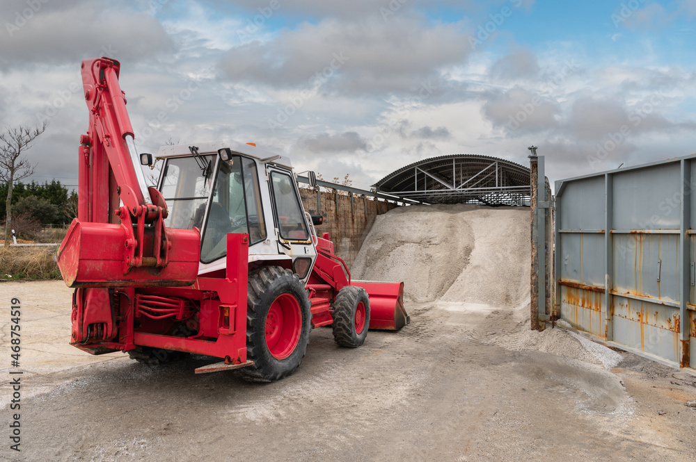 Excavator loading salt for road treatment in winter