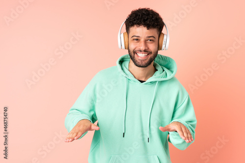 Young Moroccan man isolated on pink background listening music and dancing © luismolinero