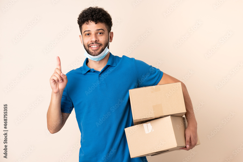 Young delivery Moroccan man isolated on beige background intending to realizes the solution while lifting a finger up