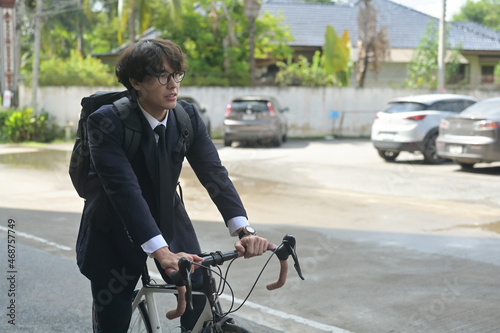 Photo of a young stylish businessman going to work by bike. Transportation in a crowded city concept. © saltdium