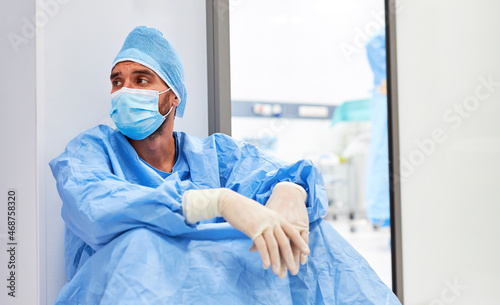 Chirurg sitzt müde und ausgebrannt vor der Intensivstation