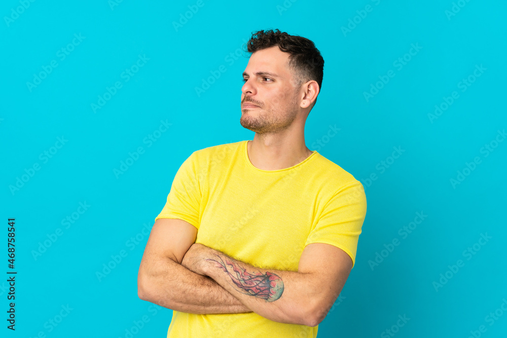 Young caucasian handsome man isolated on blue background looking to the side Young caucasian handsome man isolated on blue background looking to the side