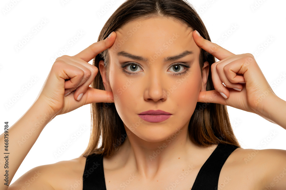 Young beautiful woman tightening her face skin with her fingers Young beautiful woman tightening her face skin with her fingers