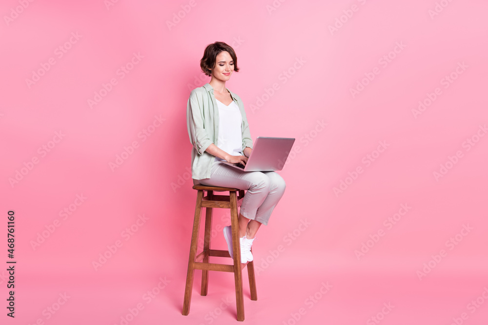 Full length photo of work bob hairdo millennial lady sit laptop wear grey green look isolated on pink color background Full length photo of work bob hairdo millennial lady sit laptop wear grey green look isolated on pink color background