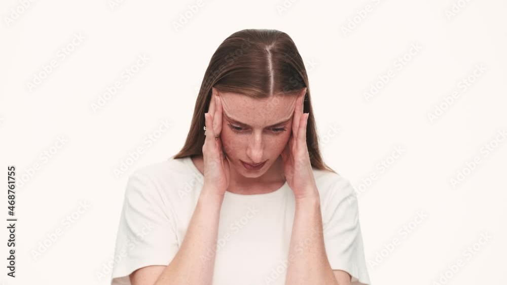Worried woman kneading her temples in white studio Worried woman kneading her temples in white studio