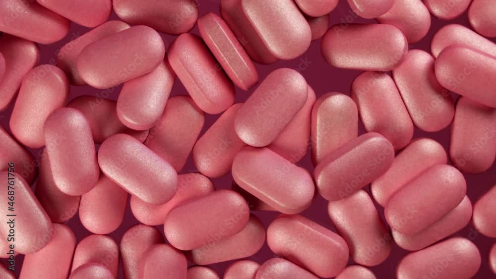 Close-up top angle view of pile of pink pills on a slow rotating platform. Detailed macro shot in studio lighting Close-up top angle view of pile of pink pills on a slow rotating platform. Detailed macro shot in studio lighting