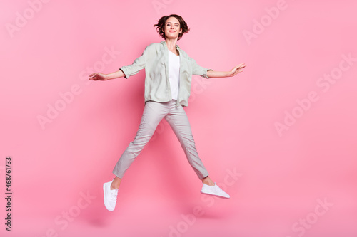 Photo of funny sweet young woman dressed beige clothes jumping high like star smiling isolated pink color background