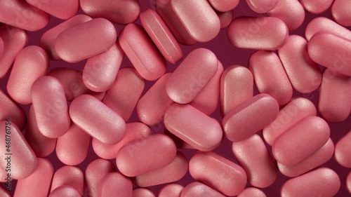 Close-up top angle view of pile of pink pills on a slow rotating platform. Detailed macro shot in studio lighting