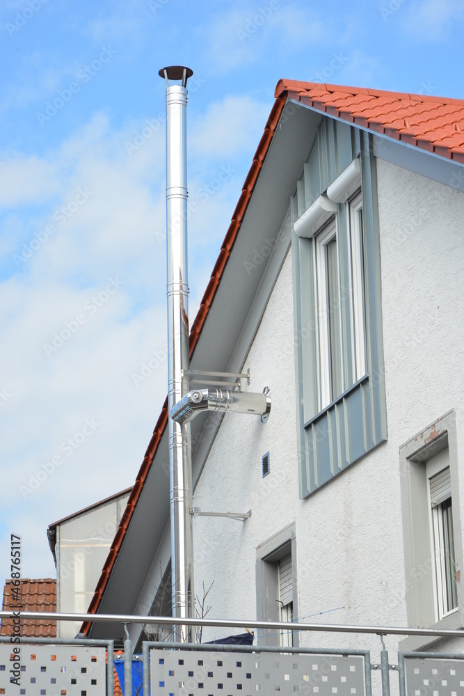 Schornstein, Außenkamin aus Edelstahl an der Fassade eines Wohnhauses