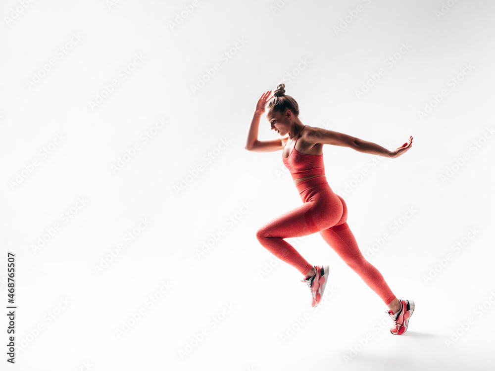 Fitness confident woman in pink sports clothing. Young beautiful model with perfect body. Female isolated on white in studio. Cheerful and happy. Jumping and running Fitness confident woman in pink sports clothing. Young beautiful model with perfect body. Female isolated on white in studio. Cheerful and happy. Jumping and running