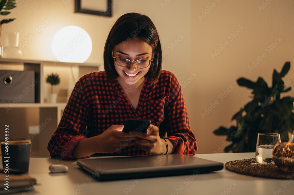 Beautiful woman using smartphone while working from home Beautiful woman using smartphone while working from home