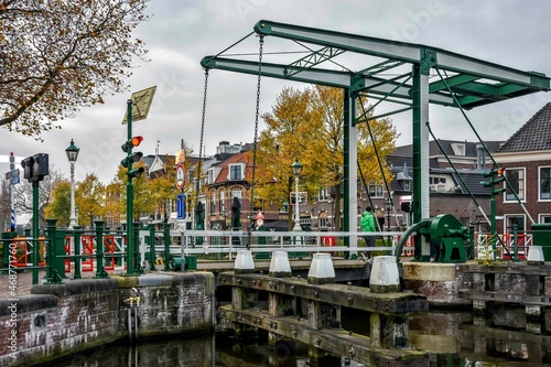 A man in a green jacket walks over a lock bridge on a cold autumn day. Leidschendam, Netherlands, Holland, Europe © Gina