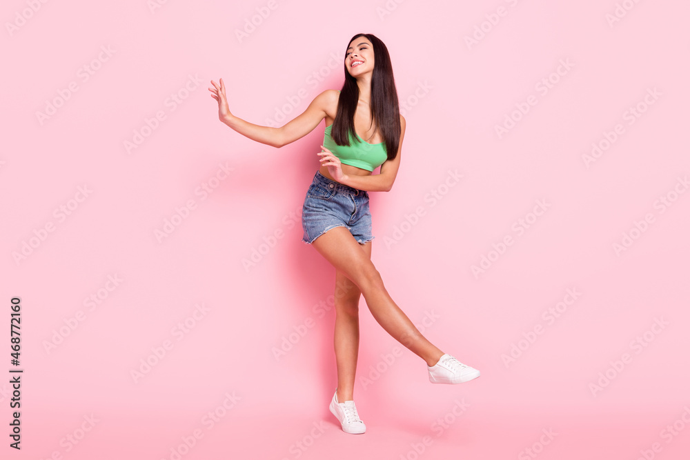 Photo of funny charming young woman hair dressed green singlet smiling dancing walking isolated pink color background